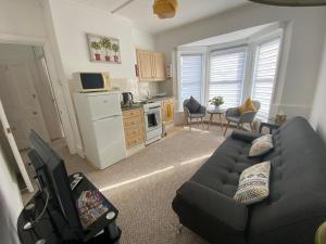 a living room with a couch and a kitchen at Penhale Holiday Flats in Eastbourne