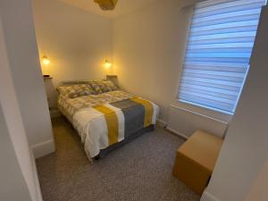 a small bedroom with a bed and a window at Penhale Holiday Flats in Eastbourne