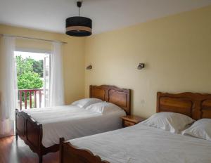 two beds in a hotel room with a window at Ferme Auberge Ibarnia in Lecumberry