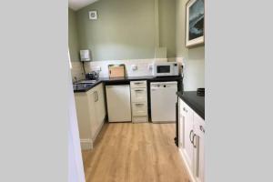 a kitchen with white appliances and a wooden floor at Private Annex near Melton Mowbray in Melton Mowbray