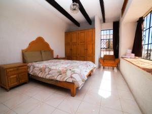 a bedroom with a bed and a chair and windows at Casa de las Cruces Taxco in Taxco de Alarcón
