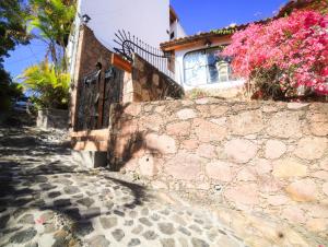 une maison avec un mur en pierre et des fleurs roses dans l'établissement Casa de las Cruces Taxco, à Taxco