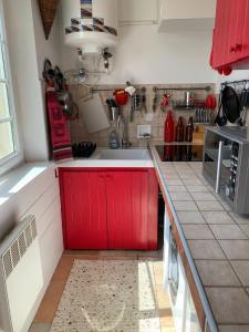 a kitchen with red cabinets and a white sink at Le Studio Rouge de la Gare in Vieux-Boucau-les-Bains