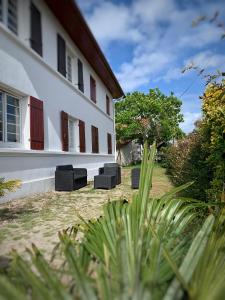 a white building with black chairs in the yard at Le Studio Rouge de la Gare in Vieux-Boucau-les-Bains