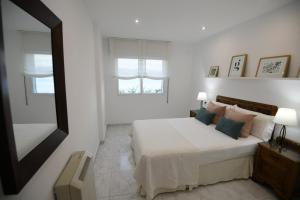 Coqueto apartamento en Raxó, Sanxenxo في راكسو: غرفة نوم بيضاء بها سرير ونافذة