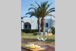 Palmaya Villa, unique seafront experience في Vaia: كوب من النبيذ الأبيض وصحن من الفاكهة