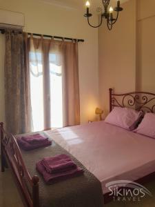 sypialnia z dużym łóżkiem z fioletową pościelą i oknem w obiekcie Kastro Elegant House w mieście Sikinos