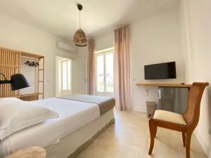 a bedroom with a bed and a chair and a television at Maison Sciscì Rooms in San Felice Circeo