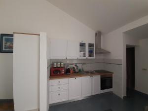 eine Küche mit weißen Schränken und einem roten Gerät in der Unterkunft Romantic Apartment by the Beach in Malinska