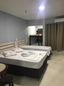 two beds in a room with tables and chairs at Apart Hotel CTC - Edifício Araras in Caldas Novas