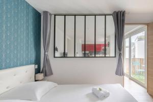 a bedroom with a white bed and a window at Logement confort moderne au pied du Front de Mer in Saint-Nazaire