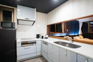 a kitchen with white cabinets and a black refrigerator at Weskii Hotel in Kanazawa