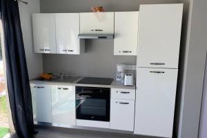 a kitchen with white cabinets and a sink and a microwave at Studio lumineux à proximité de domaines viticoles in Cairanne