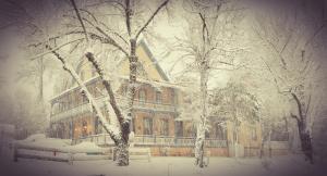 un edificio coperto di neve di fronte agli alberi di American River Inn a Georgetown