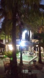 a house with a pool and palm trees at night at Pousada d'Ibiza in Itanhaém