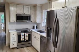 una cocina con electrodomésticos de acero inoxidable y armarios blancos en Farm House stay with soaking tub and hot tub barn en Hammond