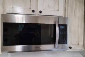 a stainless steel microwave oven in a kitchen at Farm House stay with soaking tub and hot tub barn in Hammond