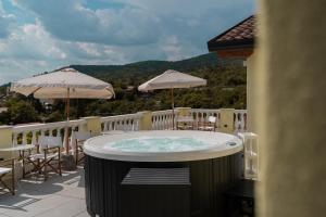 a hot tub on a balcony with tables and umbrellas at Locanda Gaudemus Boutique Hotel in Sistiana