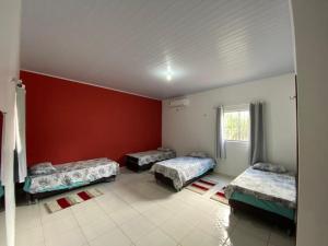 3 Betten in einem Zimmer mit roter Wand in der Unterkunft Rancho Lisboa Cocal in Queimada + 11 Fotos