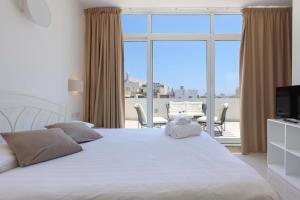 a bedroom with a large white bed and a balcony at Ta Gianni Guest House in Sliema