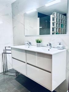 a white bathroom with two sinks and a mirror at Apartamento en la playa Arensol Cullera in Cullera