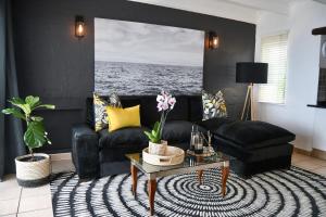 a living room with a black couch and a table at Palm Cove - 10 Thira, Santorini, best view over Thompsons Beach in Ballito