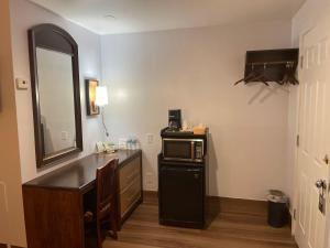 a room with a desk and a microwave and a mirror at Scottish Inn - North Tonawanda in Tonawanda