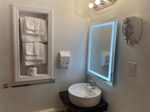 a bathroom with a sink and a mirror and towels at Scottish Inn - North Tonawanda in Tonawanda +25 photos