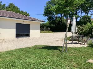 an umbrella and a table in a yard with a building at Les Écorchoux c'est chou in Tossiat +1 photo