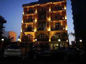 un edificio alto con coches estacionados frente a él en Hotel Eurasia en Batumi