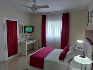 1 dormitorio con 1 cama con cortinas rojas y TV en La Graciosa, en Gran Tarajal