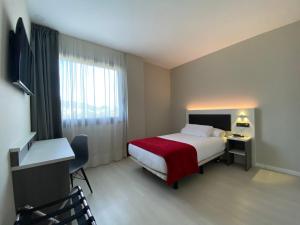 Habitación de hotel con cama con manta roja en Hotel New Bilbao Airport, en Derio