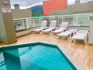 a balcony with chairs and a swimming pool on a building at Apto no Itaguá - Varanda Gourmet e Lazer completo in Ubatuba