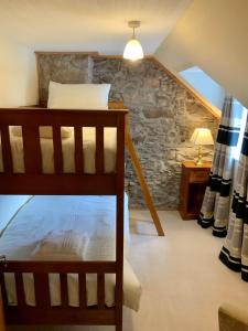 une chambre avec un lit superposé et un mur en pierre dans l'établissement No 10 The Cottage, à Inverness