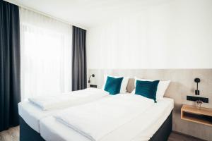 a bedroom with two white beds with blue pillows at SmartLiving Apartments München in Munich