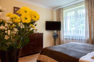 1 dormitorio con 1 cama y un jarrón de flores amarillas en Apartament u Janka en Wieliczka