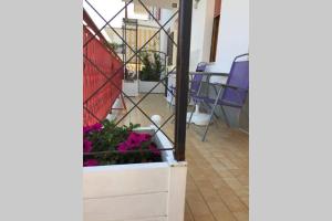 カンポマリーノにあるAppartamento in Residence Santa Monicaの紫の花とテーブルと椅子が備わるバルコニー +4枚の写真