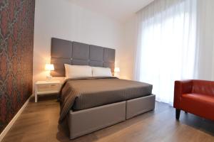 1 dormitorio con 1 cama grande y 1 silla roja en Maison Flaminio, en Roma