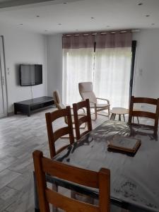 een woonkamer met een tafel en stoelen en een flatscreen-tv bij Maison petit ion jean mi et flo in Vendays-Montalivet