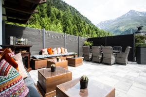 un patio con sofás, mesas y una montaña en Verwöhn-Harmoniehotel Mandarfnerhof en Sankt Leonhard im Pitztal