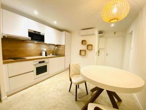 a white kitchen with a white table and chairs at Feel@Home Nemausus « Le 21 » in Nîmes