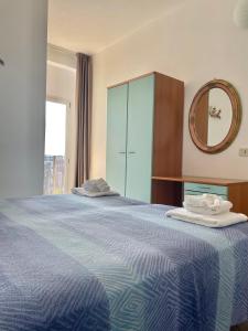- une chambre avec un lit bleu et un miroir dans l'établissement Hotel Blumen, à Rimini