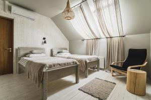 a bedroom with two beds and a chair and a window at Guest House Garoza in Tūja