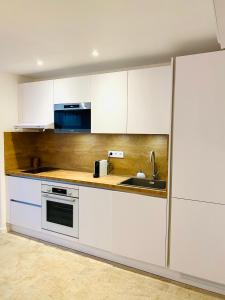 a kitchen with white cabinets and a sink at Feel@Home Nemausus « Le 21 » in Nîmes