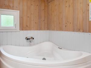 a white bath tub in a bathroom with wooden walls at 6 person holiday home in Jerup in Jerup