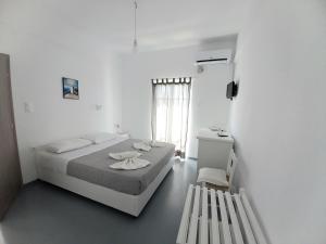 a white bedroom with a bed and a window at Hotel Anezina in Drios
