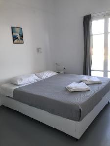 a bed in a white room with two towels on it at Hotel Anezina in Drios