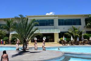 a hotel swimming pool with a palm tree and a building at Lacqua diRoma 1 - Apartamentos JN in Caldas Novas