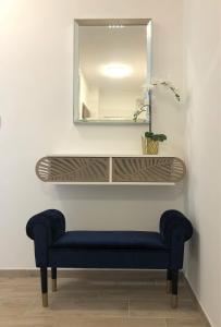 a shelf with a blue bench and a mirror at Glamour Apartman in Tapolca