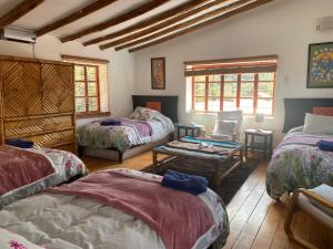 a room with three beds and a table at Casa de la Gringa Mountain House in Cusco